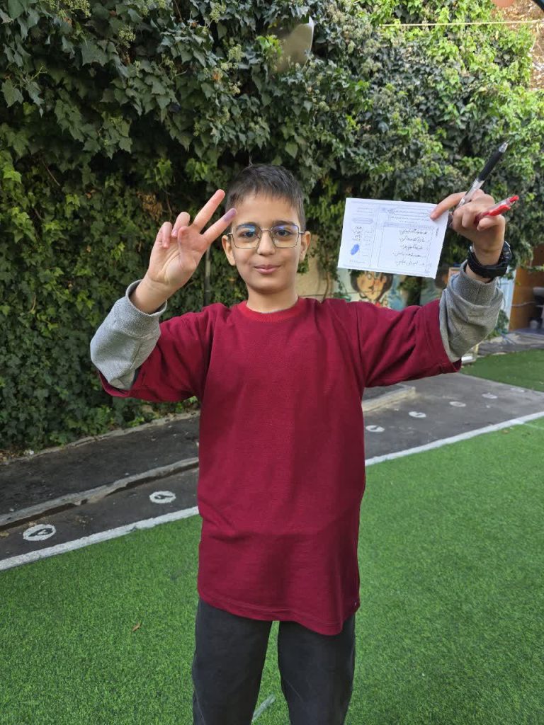 دانش آموز در حال نشان دادن برگه رای خود در روز انتخابات‌ شورای دانش آموزی مدرسه نورامیر